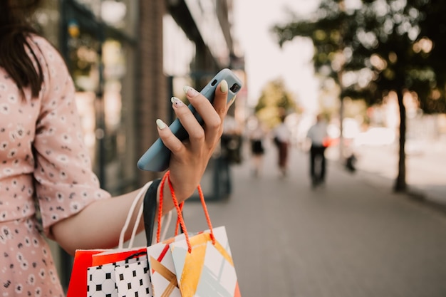 Señora sostenga muchas bolsas y teléfono después de ir de compras