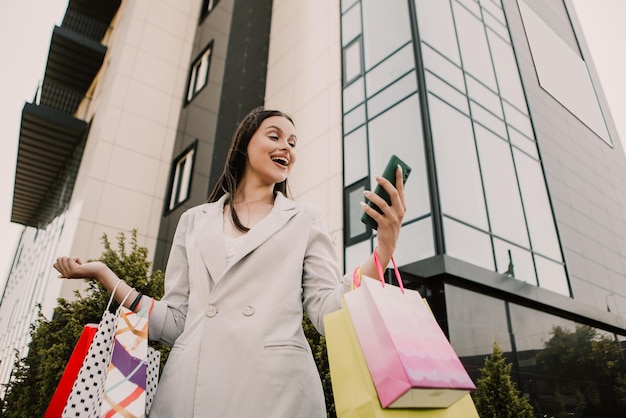 Señora sostenga muchas bolsas y teléfono después de ir de compras