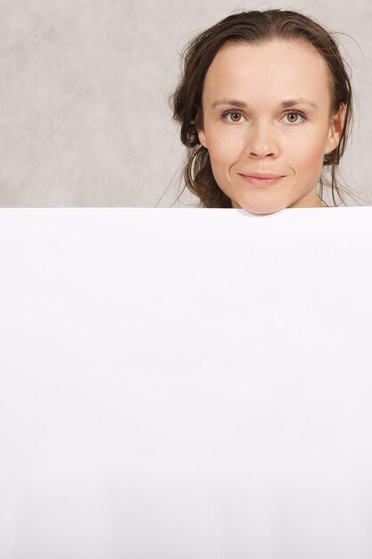 Foto señorita de entre 30 y 40 años guarda una hoja de papel en blanco