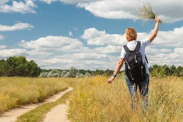 Señorita caminando por un camino rural. Caminante con mochila caminando al aire libre en la naturaleza. Viajero caminando por el sendero del país al aire libre. Estilo de vida activo y saludable