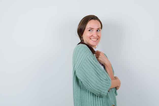 Foto señorita en chaqueta de punto posando mientras mira hacia arriba y parece feliz.