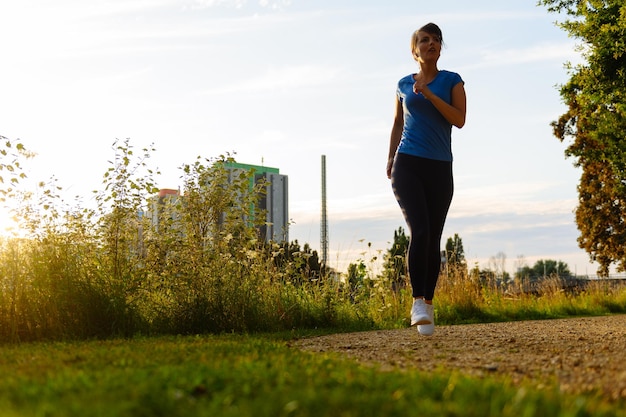 Foto señorita corriendo en un camino rural durante la puesta de sol