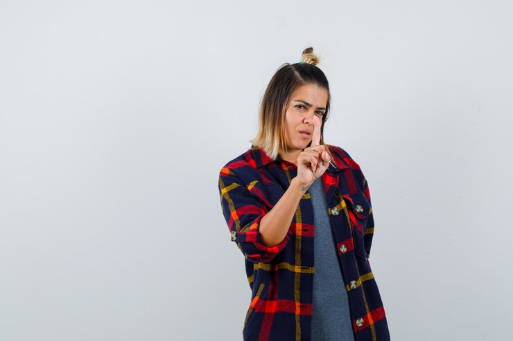 Foto señorita mostrando un dedo en camisa casual a cuadros y mirando pensativo, vista frontal.
