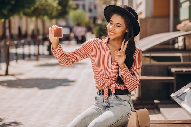 Señorita positiva haciendo gesto de paz y tomando selfie