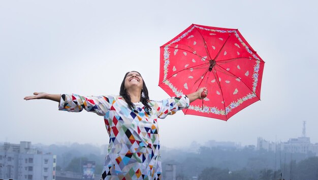 Una señorita sosteniendo paraguas y disfrutando del clima lluvioso durante la temporada de monzones en la India