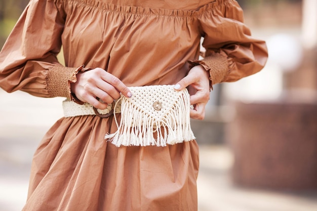 Señorita con vestido marrón con bolsa de cinturón de macramé posando en la calle de la ciudad europea Copia al aire libre espacio vacío para texto