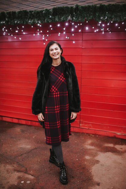 Señorita en vestido de pie cerca de la casa decorada para Navidad