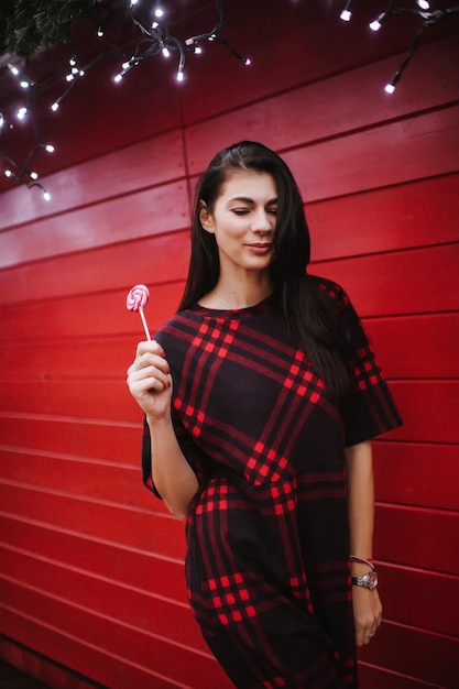 Señorita en vestido de pie cerca de la casa decorada para Navidad