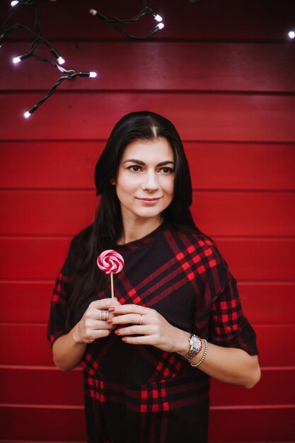 Señorita en vestido de pie cerca de la casa decorada para Navidad