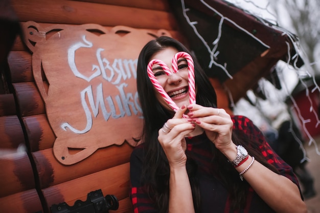 Foto señorita en vestido de pie cerca de la casa decorada para navidad