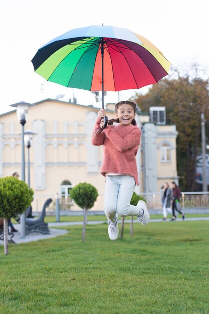 Sensação de liberdade Guarda-chuva multicolorido para menina feliz livre Menina livre com guarda-chuva Humor positivo no outono Arco-íris depois da chuva Criança otimista e alegre Primavera Salto de liberdade