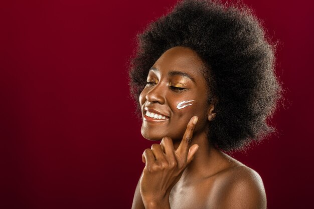 Sensação perfeita. mulher alegre e feliz fechando os olhos enquanto aplica o creme facial