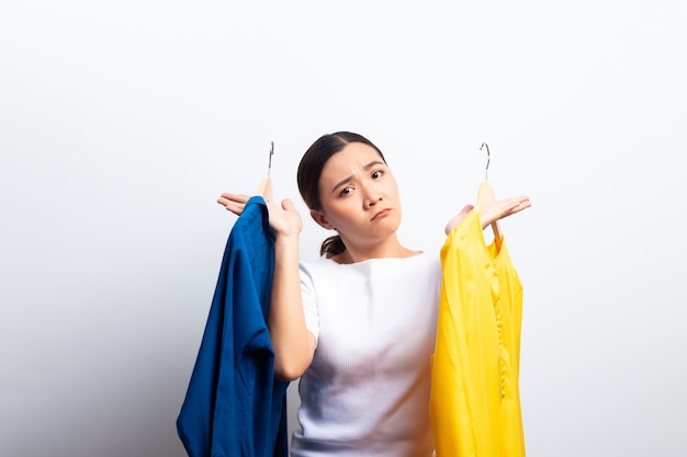 La sensación de la mujer confunde para elegir la blusa aislada sobre el fondo blanco