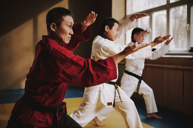 Sensei e dois estudantes de artes marciais fazendo posições juntos.