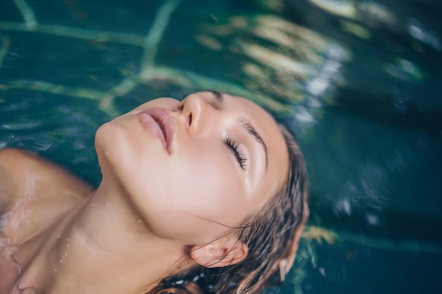 Foto sensual joven delgada relajante en la piscina al aire libre