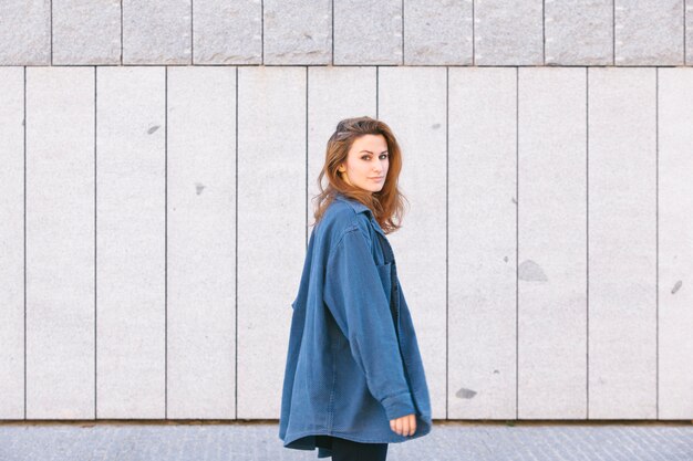 Sensual joven mujer de cabello castaño vestida con una camisa de hombres grandes aislada en una pared gris