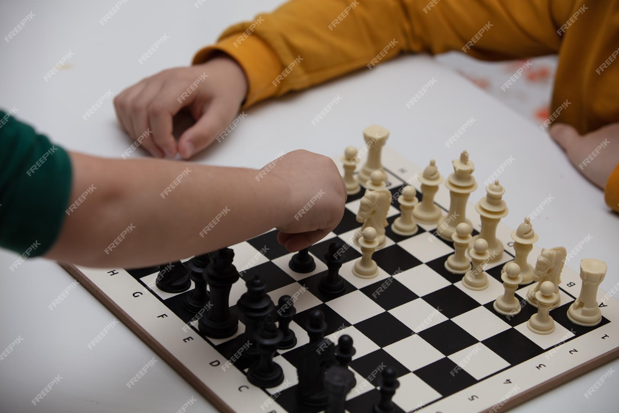 Senta-se à mesa e joga xadrez a criança concentra-se no jogo