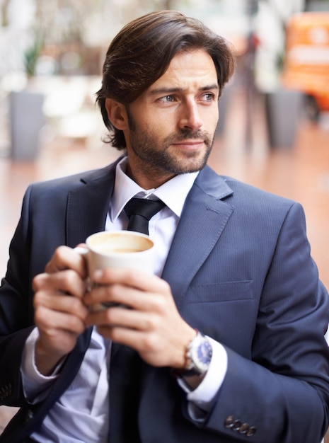 Sentado assistindo o mundo passar Um empresário atencioso bebendo café ao ar livre em uma cafeteria