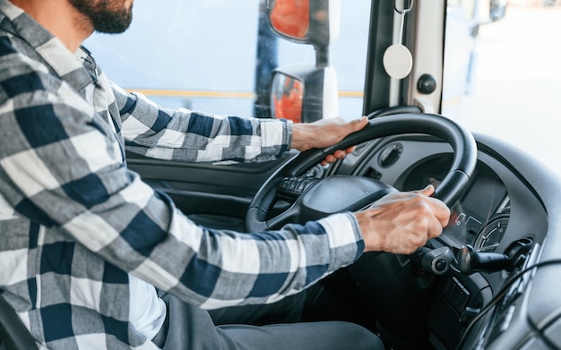 Foto sentado en la cabina al volante el joven camionero está con su vehículo durante el día