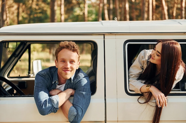 Sentado en el coche Una pareja joven viaja juntos por el bosque durante el día