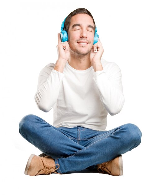 Foto sentado feliz joven utilizando un auriculares