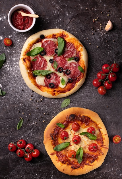 Sentar planas de dos pizzas con tomate y albahaca en el cuadro negro