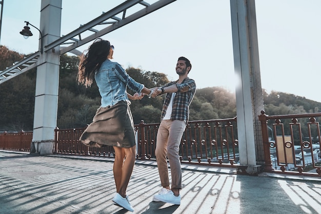 Sentimentos puros. Comprimento total do lindo jovem casal de mãos dadas e girando