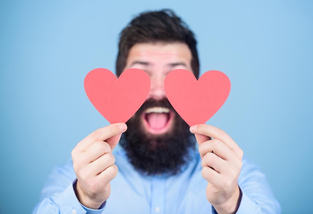 Sentindo amor. Conceito de namoro e relações. Feliz no amor. O amor é incrível. Hipster barbudo de homem com cartão de dia dos namorados de coração. Celebre o amor. Cara atraente com barba e bigode em clima romântico.