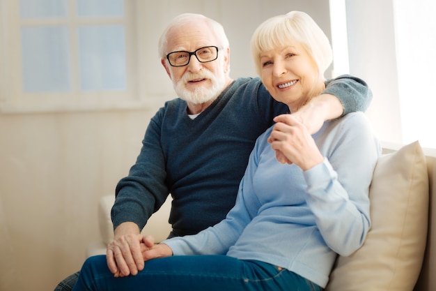 Sentindo felicidade. mulher encantadora segurando as mãos do marido e sorrindo enquanto olha para a frente