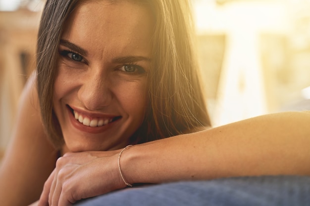 Sentindo felicidade. Mulher positivamente encantada, apoiando o cotovelo na cama enquanto demonstra seu sorriso