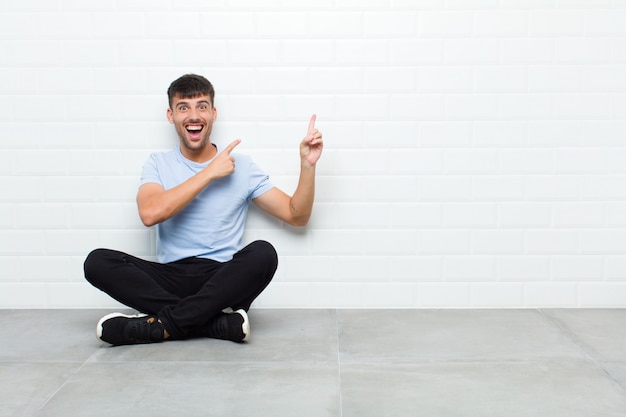 sentindo-se alegre e surpreso, sorrindo com uma expressão chocada e apontando para o lado