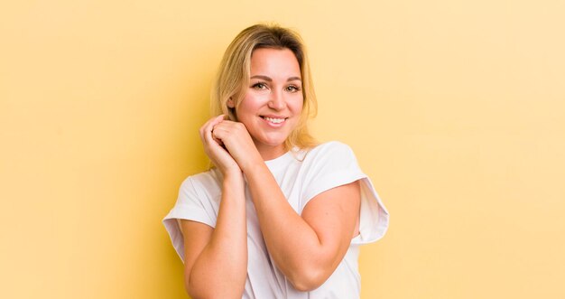 Sentindo-se apaixonado e bonito adorável e feliz sorrindo romanticamente com as mãos ao lado do rosto