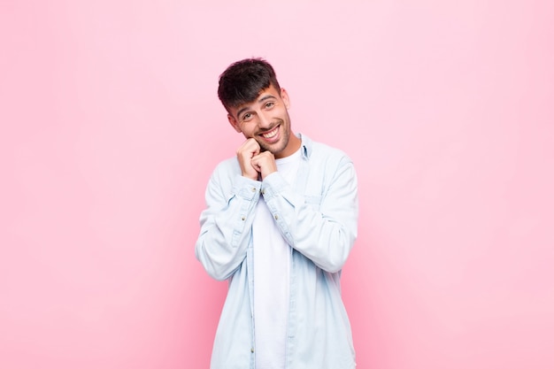 sentindo-se apaixonado e bonito, adorável e feliz, sorrindo romanticamente com as mãos ao lado do rosto