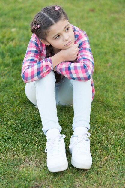 Foto sentindo-se cansada e deprimida, menina triste relaxa na grama verde parques e ao ar livre natureza da primavera piquenique de verão menina da escola pequena com cabelo da moda primavera depressão e tristeza quando estou sozinho