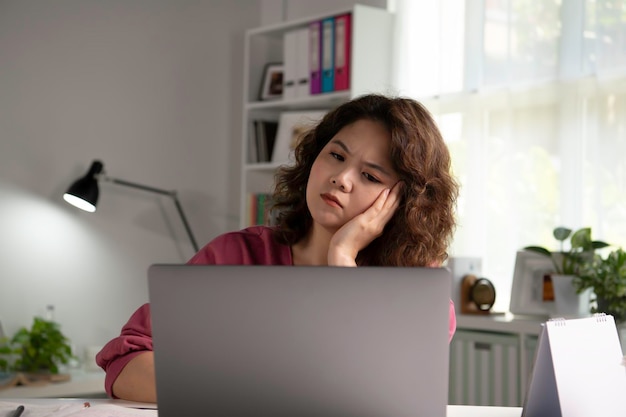 Sentindo-se cansado e estressado. Jovem mulher asiática sentada olhando profundamente exausta e cansada durante o trabalho em casa usando o laptop. Trabalhadora de estudante asiática cansada e sobrecarregada olhando exhau