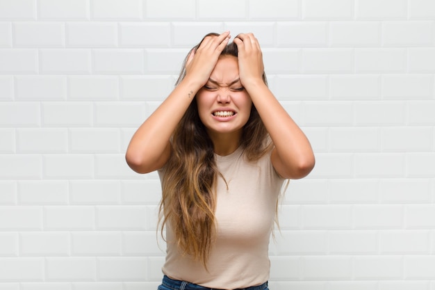 sentindo-se estressado e ansioso, deprimido e frustrado com uma dor de cabeça, levando ambas as mãos à cabeça