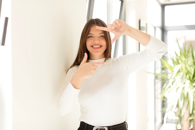 sentindo-se feliz, amigável e positivo, sorrindo e fazendo um retrato ou moldura com as mãos