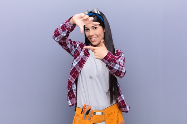 sentindo-se feliz, amigável e positivo, sorrindo e fazendo um retrato ou moldura com as mãos