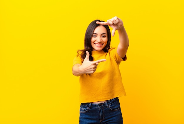 Sentindo-se feliz, amigável e positivo, sorrindo e fazendo um retrato ou moldura com as mãos