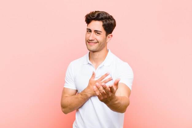 Sentindo-se feliz e apaixonado, sorrindo com uma mão ao lado do coração e a outra esticada na frente