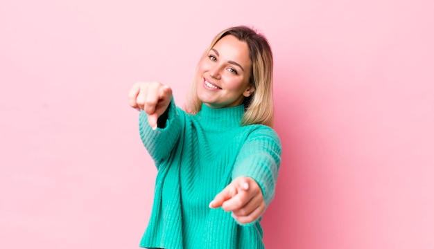 Sentindo-se feliz e confiante apontando para a câmera com as duas mãos e rindo escolhendo você