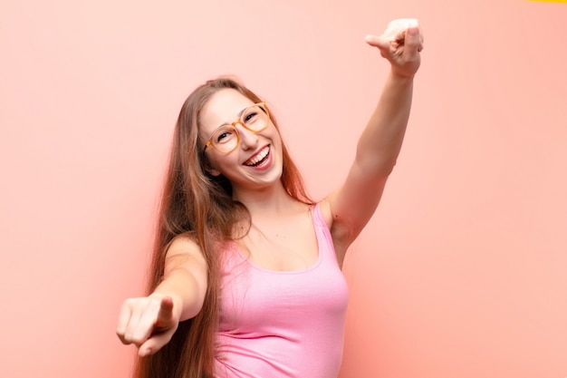 sentindo-se feliz e confiante, apontando para a câmera com as duas mãos e rindo, escolhendo você