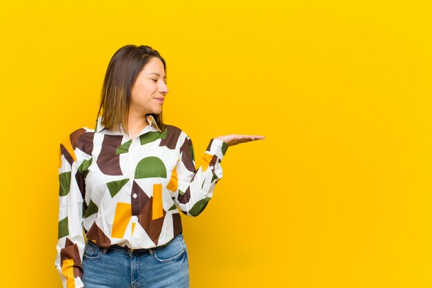 sentindo-se feliz e sorrindo casualmente, olhando para um objeto ou conceito realizado na mão do lado