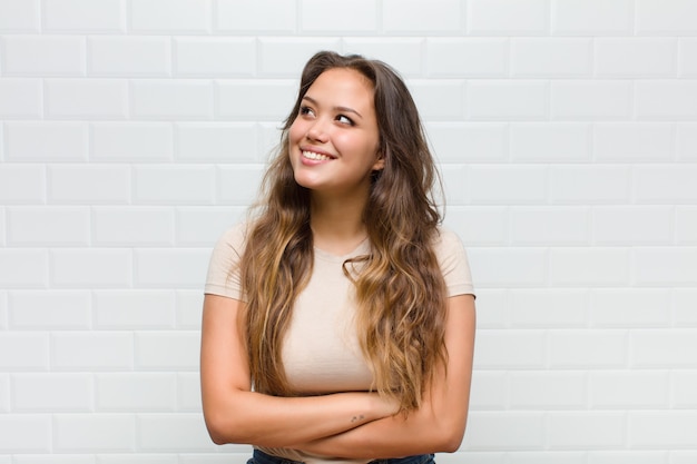 sentindo-se feliz, orgulhoso e esperançoso, imaginando ou pensando, olhando para cima para copiar o espaço de braços cruzados