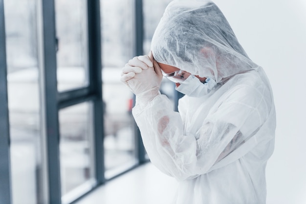 Sentindo-se mal, cansado e deprimido. Retrato de cientista médico feminino no jaleco, óculos de defesa e máscara