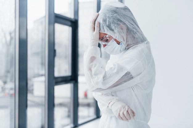 Sentindo-se mal, cansado e deprimido. retrato de cientista médico feminino no jaleco, óculos de defesa e máscara