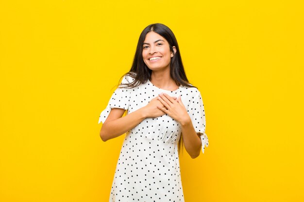 sentindo-se romântico, feliz e apaixonado, sorrindo alegremente e de mãos dadas perto do coração