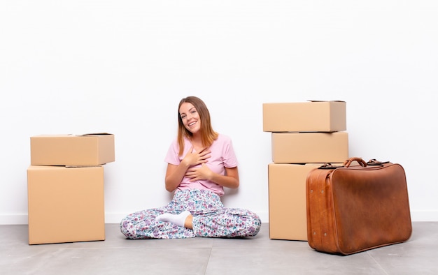 sentindo-se romântico, feliz e apaixonado, sorrindo alegremente e segurando as mãos perto do coração