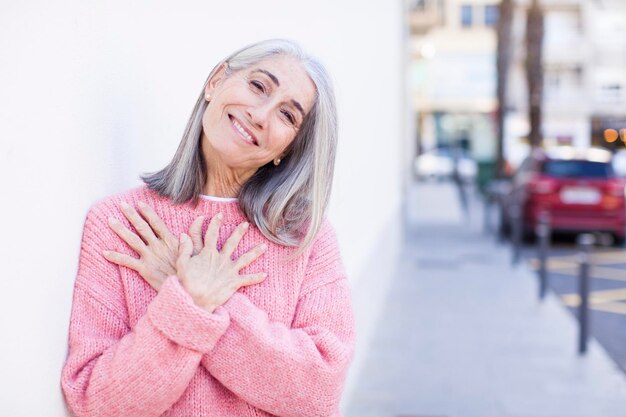 Sentindo-se romântico feliz e apaixonado sorrindo alegremente e segurando as mãos perto do coração