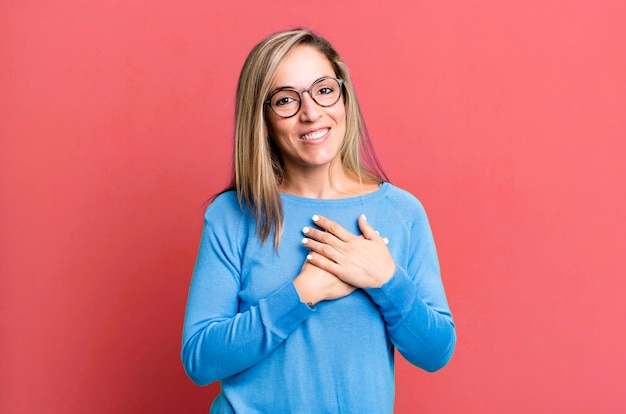 Sentindo-se romântico feliz e apaixonado sorrindo alegremente e segurando as mãos perto do coração